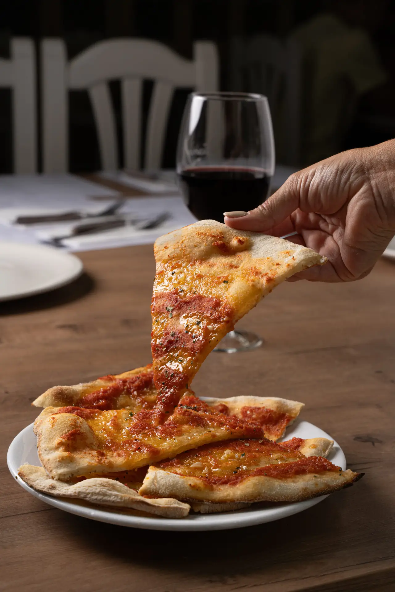 Mano cogiendo una porción de pizza de un plato en Pizzería Vesubio.