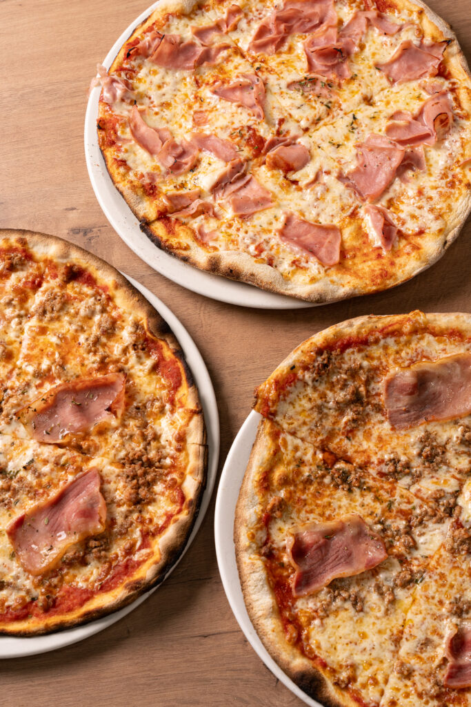 Tres pizzas de Pizzería Vesubio servidas en platos, listas para compartir